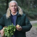 Garden Guide - Man in Green Fur Coat Holding Vegetable and Apple Fruit